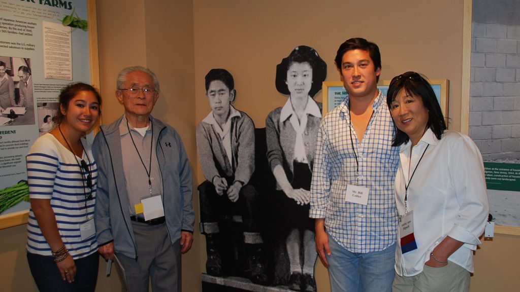 William Higuchi and his family stand with a photo of himself and his wife, Setsuko, during the war.